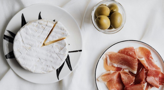 Das Bild zeigt Oliven und Parmaschinken einer Antipasti-Platte.